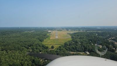 View of an airport runway surrounded by greenery from a small aircraft.