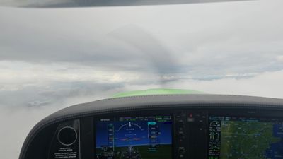 View from a cockpit flying above the clouds with instruments visible.