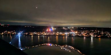 Nighttime cityscape with reflections on water under a cloudy sky.