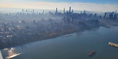 Aerial view of a foggy city skyline with water in the foreground.
